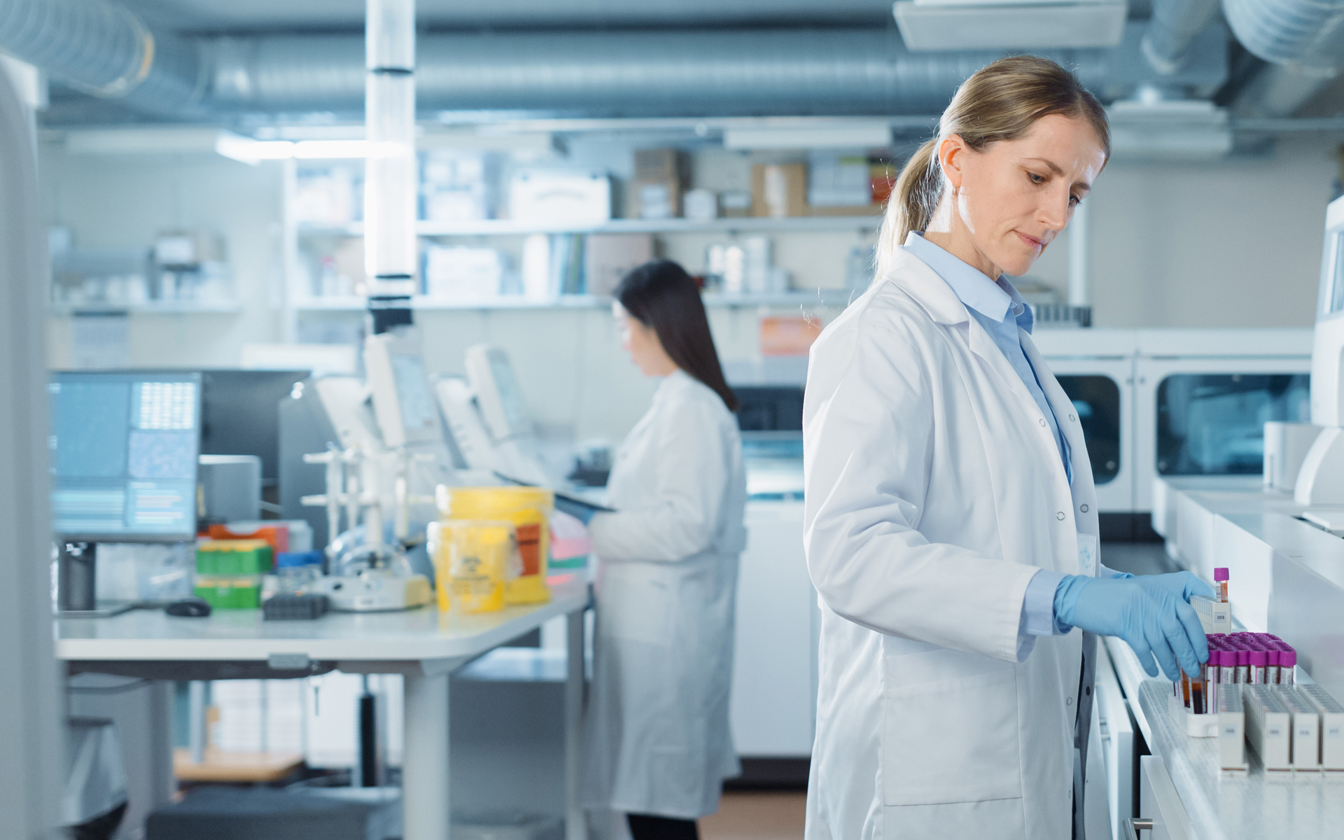 Two lab workers handling medical equipment.